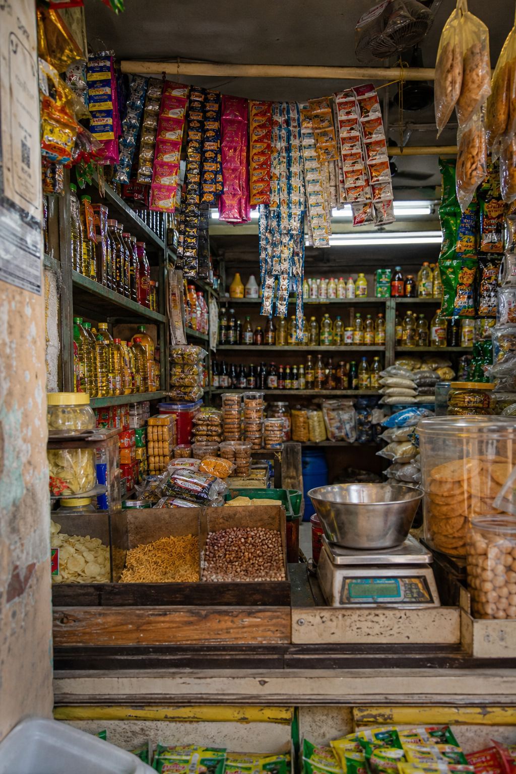 Packed shelves and hanging packets inside a neighbourhood grocery.
